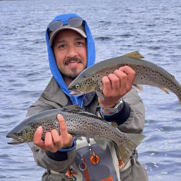 Man holds two sea trout caught while fly fishing in Kristiansand